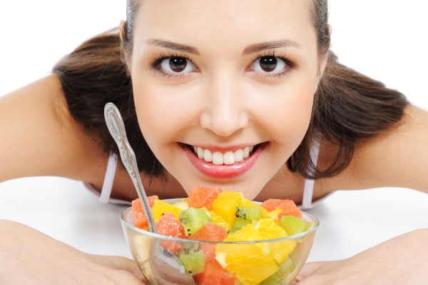 photo beautiful young female face under the bowl with fruit salad