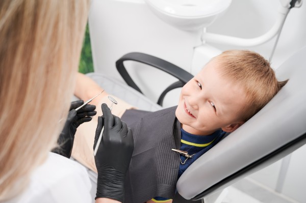 photo cheerful little boy sitting in dental chair in dental office