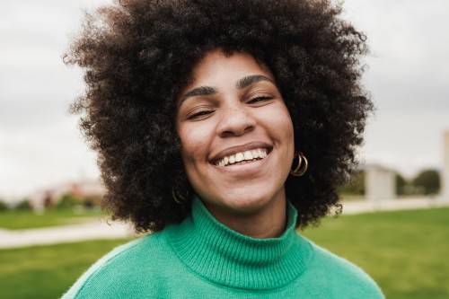 Woman smiling outside wearing a green sweater