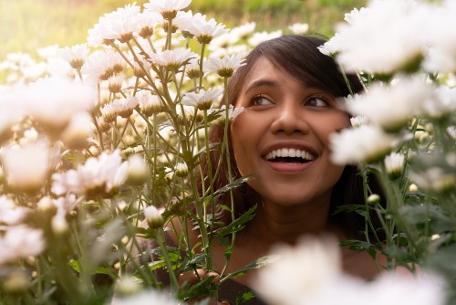 Woman smiling, white flowers are around her face.